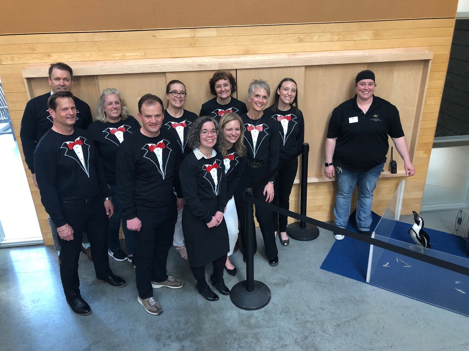 Board members dressed in tuxedos pose next to Cupid the penguin at Como Zoo.